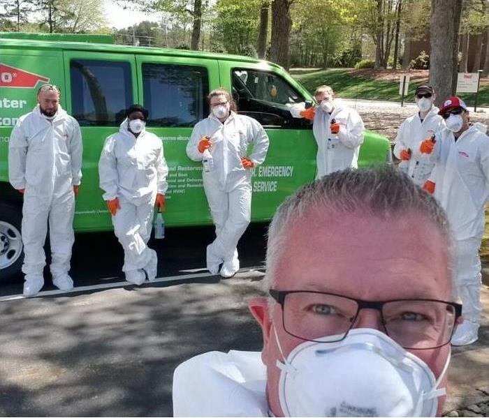 Group of production technicians taking a selfie in front of SERVPRO vehicle on bright sunny day.