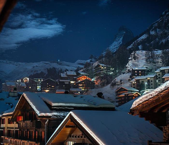roofs of a village in the alps, covered in snow at night